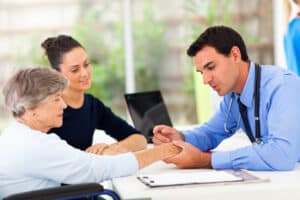Doctor looking at elderly patient’s hand for carpal tunnel syndrome and arthritis.