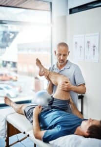 Physical therapist assessing a male client's leg pain, providing expert care and rehabilitation for sports injuries and post-orthopedic surgery recovery.